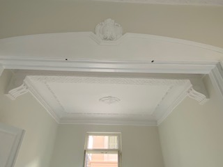 Ornate plaster cornice and decorated doorway in a neoclassical room
