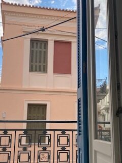 Neoclassical facade and wrought-iron balcony seen from a window